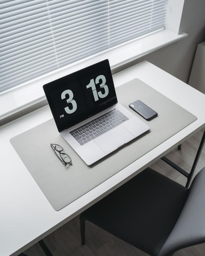 image of a desk with a laptop and large clock on the screen