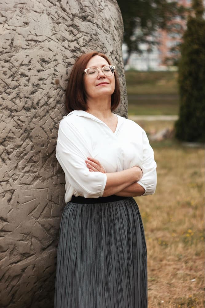 a woman leans on a rock, resting